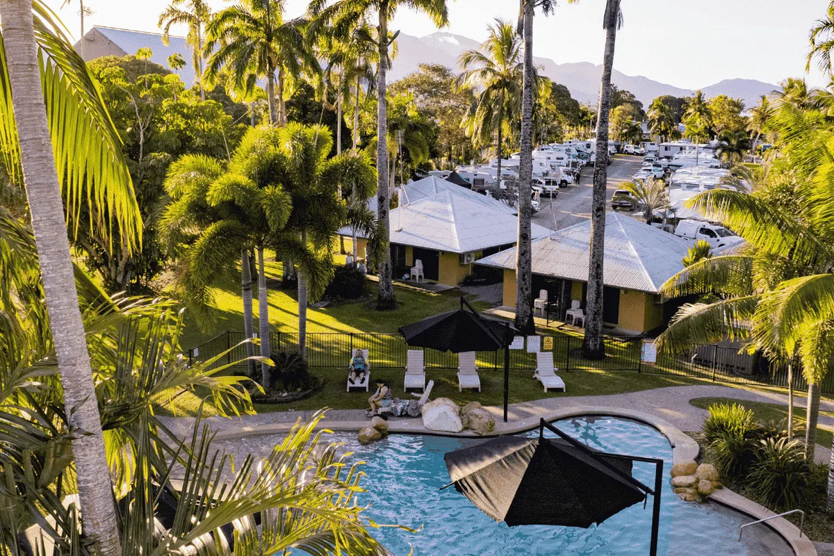 An aerial view of BIG4 Lucinda Holiday Park pool with cabins and palm trees in the background