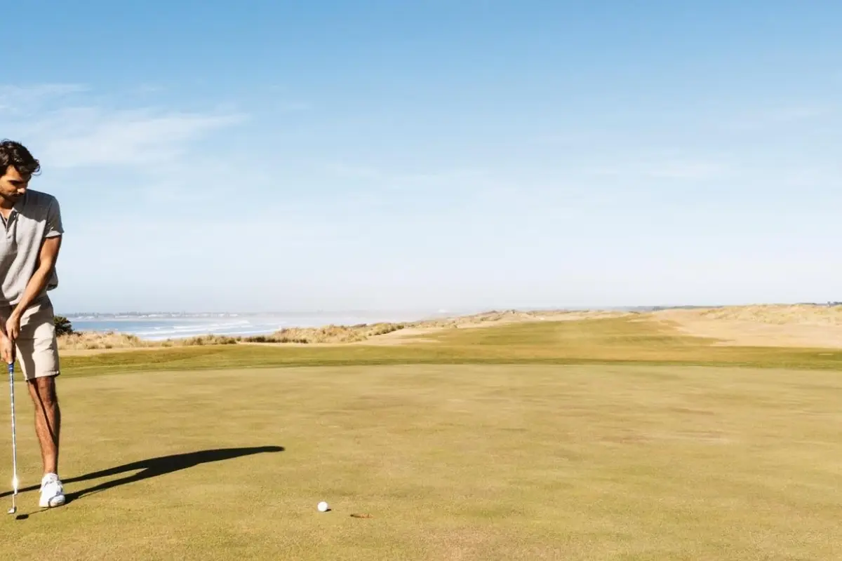 Golfer lining up a putt on a coastal golf course with ocean views in the background.