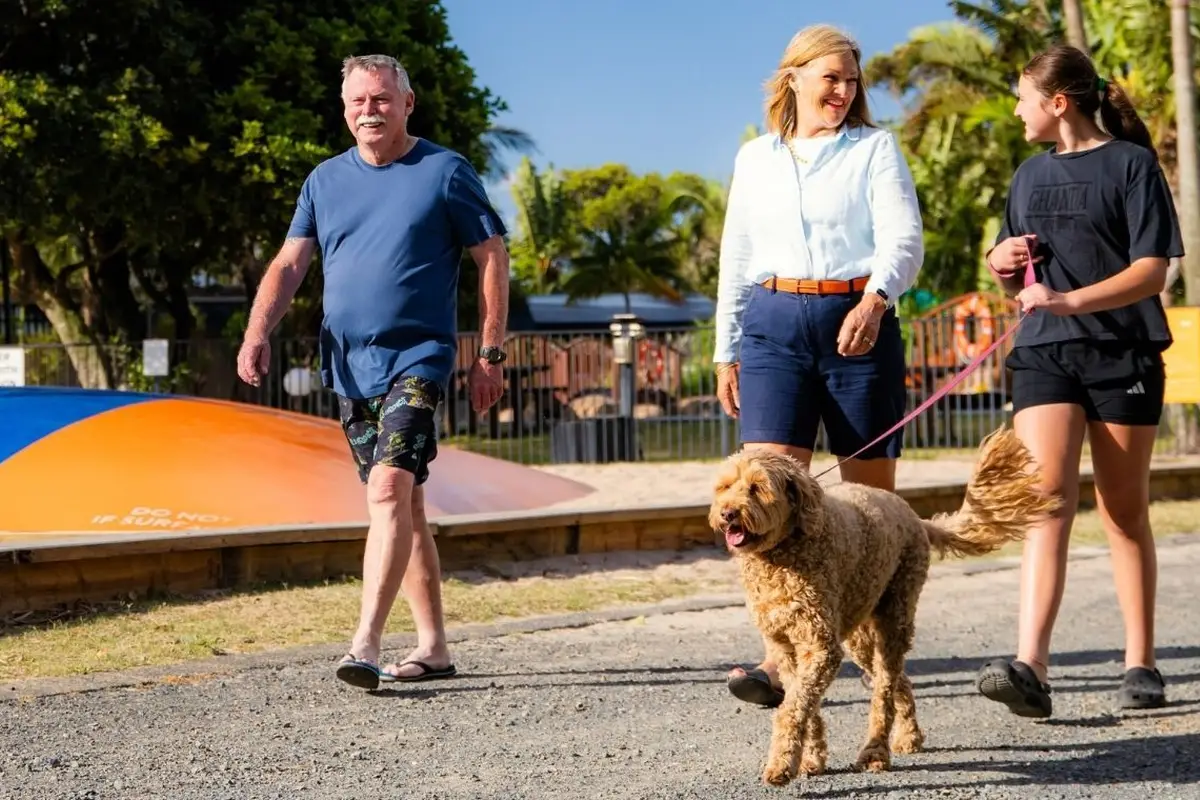 Guests walking their dog at a pet-friendly holiday park, with caravan and camping sites nearby.