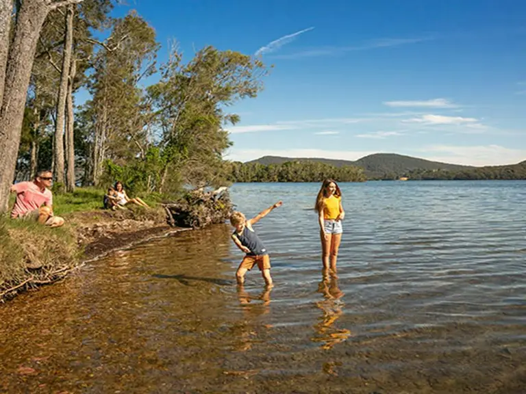 Children wading in the shallow waters of Wallis Lake in Booti Booti National Park near Forster, NSW.