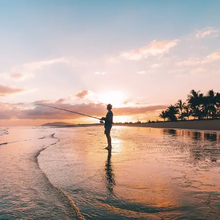 A silhouette of a man fishing on the beach at Lucinda, with the sunset in the background
