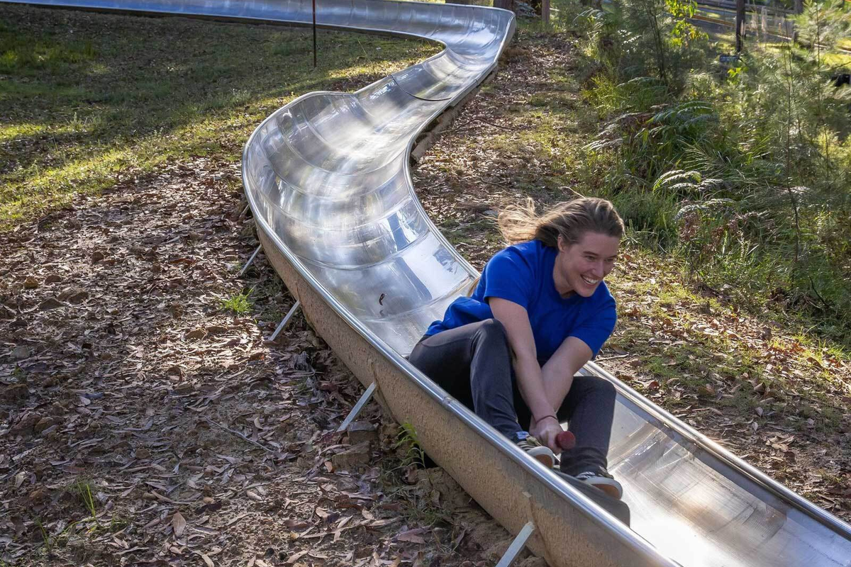 Woman enjoying the toboggan ride through bushland at Magic Mountain Merimbula, a popular family attraction on the NSW Sapphire Coast.