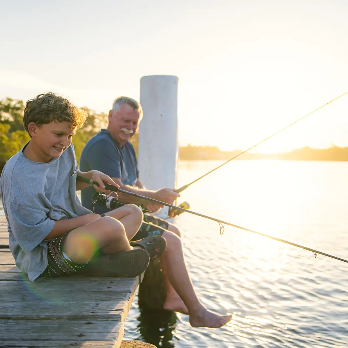 A grandfather and grandson are fishing on a pier in Manning Point