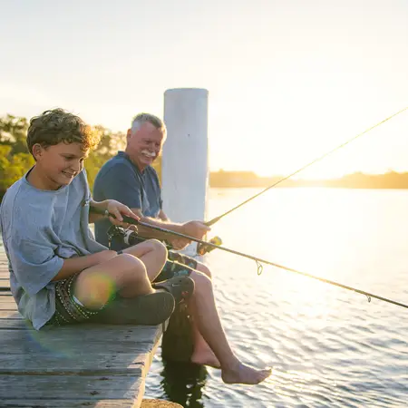 A grandfather and grandson are fishing on a pier in Manning Point