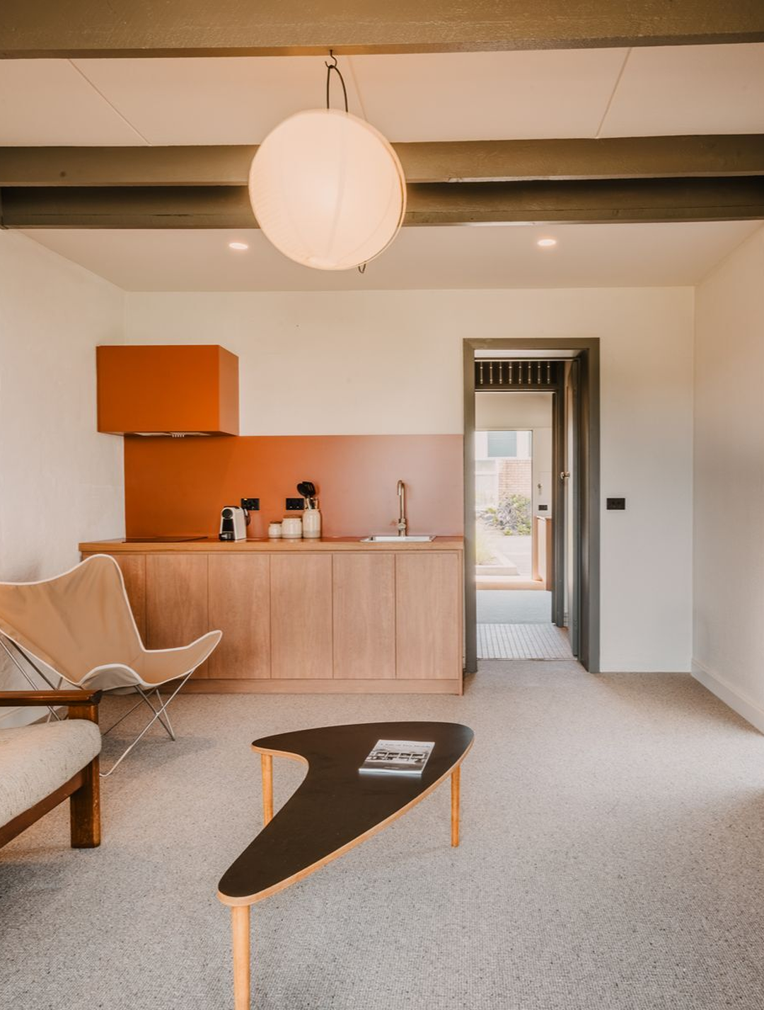 Merimbula motels: renovated suite at Black Dolphin Motel featuring a lounge area, kitchenette and mid-century-inspired interiors