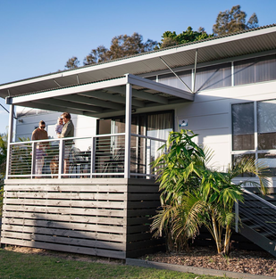 Guests relaxing on the deck of cabin accommodation at Barlings Beach Holiday Park