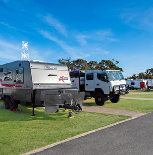 Merimbula caravan park: caravans and campervans on grassy powered sites at Black Dolphin Holiday Park