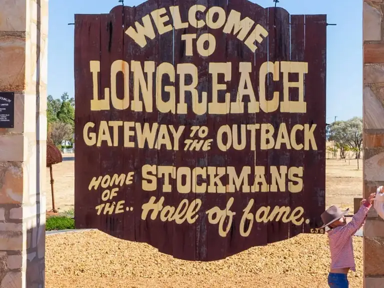 Visitors posing beside the Welcome to Longreach sign at the gateway to Queensland’s Outback.